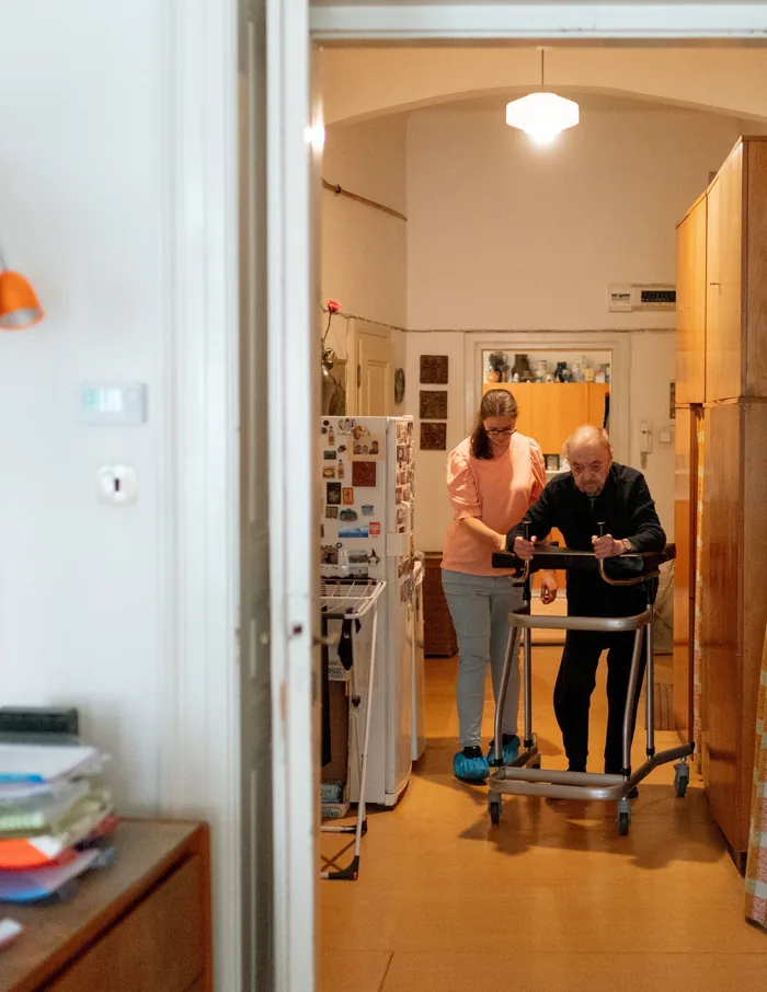 Ambulante Grundpflege: Pflegekraft unterstützt Senior bei der Mobilität zuhause